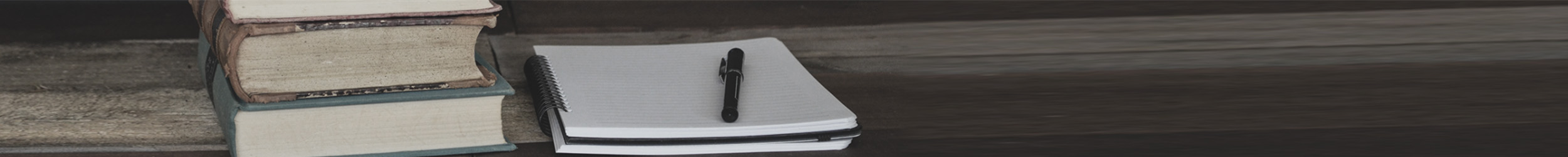 Close-up of old books, a notebook, and a pen on a table Close-up of old books, a notebook, and a pen on a table