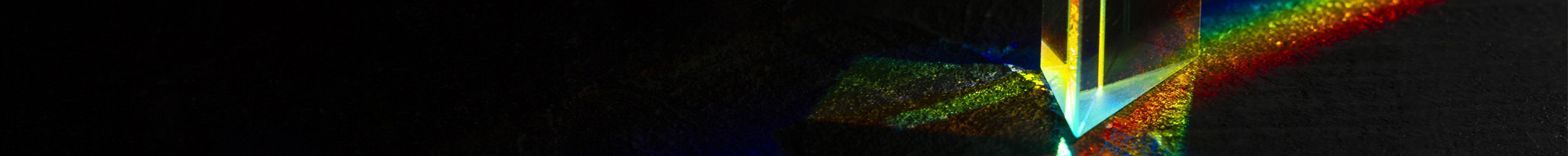 Light passing through glass, forming a rainbow of colors against a dark background. Light passing through glass, forming a rainbow of colors against a dark background.