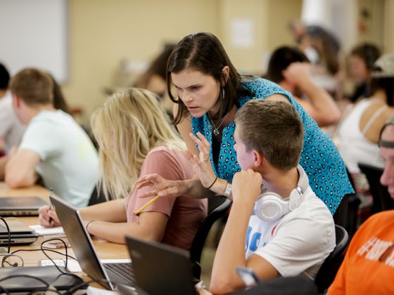 Teacher explaining a lesson to students in a computer lab.